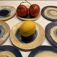 Set of 8 handmade ceramic dessert plates arranged with fruit to demonstrate size and design variety.