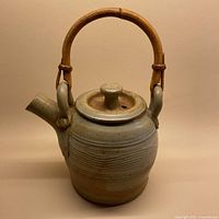 Front view of the ceramic teapot with bamboo handle showing the shape, spout, and lid.