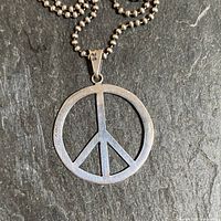 Close-up of the sterling silver peace sign pendant showing the 925 stamp on the bail and the round hollow design of the peace symbol.
