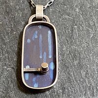 Front close-up of the vintage sterling silver pendant showing the blue synthetic rectangular center with silver bezel and rod sphere detail on bottom left corner