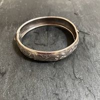 Top view showing the floral etched design on the bracelet surface and oval shape.