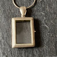 Front view of the rectangular silver glass locket showing the frame and bail for chain attachment.