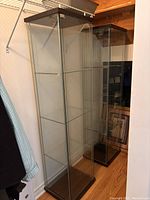 Two glass shelving units placed side by side inside a closet, viewed from front.