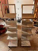 Front view of two industrial shelving units side by side with perforated metal shelves on angled racks and wheeled bases.