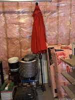 Two red patio umbrellas in storage, one folded and standing, the other shown in different garage setting.