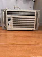 Front view of white RiteTemp window air conditioner on hardwood floor.