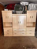 Front view of three light wood dressers with closed doors and drawers.