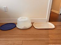 Three plastic serving trays: blue lid, white cake tray with cover, white rectangular tray