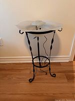 Full view of Ionic mist light lamp on decorative metal stand with curled feet and wavy scroll design on legs.