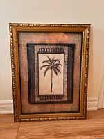 Framed palm tree picture shown against a neutral wall and hardwood floor for size reference.