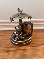 Photo of pewter carousel photo frame featuring a teddy bear, baby photo, crescent moon, and star decorations
