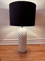 Full view of lamp showing white ceramic quilted diamond patterned base with rhinestones and black fabric cylindrical shade.