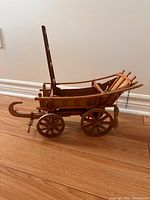 Side view of vintage wooden horse carriage model showing spoked wheels, curved runners, and ladder-style backrest