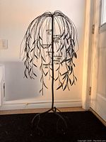 Front view of the steel weeping willow tree candle holder with no candles lit, showing the leaf-like metal details and branch structure.