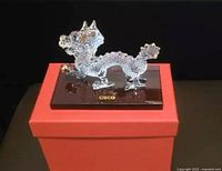 Glass Chinese Zodiac Dragon figurine with gold accents on black base displayed on red box.