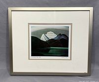 Full frontal image of framed Lawren Harris print showing mountaintop and lake scene in muted tones with mat and silver frame.