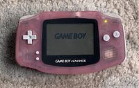 Front view of pink transparent Nintendo GameBoy Advance handheld, powered on showing GameBoy logo on screen, front buttons visible.