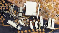 Full lot laid out on carpet showing Nintendo Wii console with all accessories including controllers, sensor bar, cables, and MotionPlus accessory.