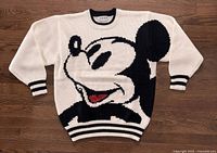 Front view of vintage ERNY Mickey Mouse sweater laid flat, showing the large graphic of Mickey Mouse's face in black, white, and red on cream background.