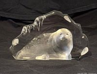 Front view of the glass sculpture depicting a seal with an icy backdrop and icicles, with visible label on the front identifying the artist.