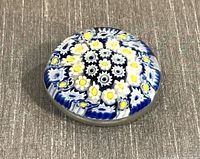 Top angled view of the round vintage Murano Millefiori glass paperweight showing floral pattern in white, yellow and blue.