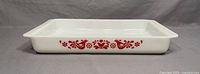 Side view of vintage Pyrex lasagna tray showing red Friendship pattern on white glass.