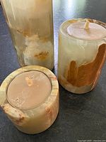 Three agate stone tealight holders with beeswax candles on a dark surface, showing top and side angles with natural stone colors and textures.