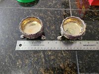 Pair of silver salt cellars side by side with ruler for scale showing approximately 2.25 inches diameter.