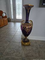 Tall full view of the purple and gold ornate reproduction urn standing on floor showing its height and decorative handles.