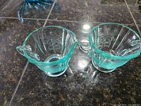 Top-down photo showing aqua depression glass cream and sugar pieces with vertical ribbed design and handles.