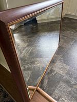 Photo showing the beveled glass mirror angled to display the reflective surface and wooden frame with decorative edging.