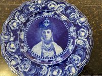 Photo showing full view of the circular flow blue plate with portrait of Queen Alexandra in center and floral patterned border