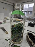 Clear glass jar partially filled with vintage glass marbles, showing their color and shape distinctly inside the jar.