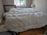 Full view of large king size white quilted duvet on a bed, showing overall condition and size.