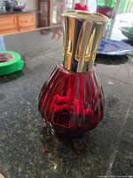 Front view of the red fluted glass Lampe Berger lamp showing gold-tone metal diffuser cap on top.