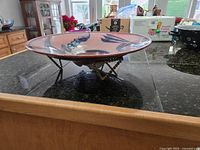 Side view of large pottery bowl on metal stand showing bowl shape and stand design