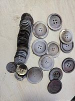 Stack and scattered view of carved mother of pearl buttons showing different sizes and colors