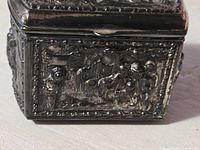 Close-up of an embossed side panel showing figures and decorative elements in relief on the metal surface with some paint wear.