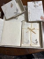 Stationery set items including boxes, photo album, notepad, and envelope with floral dried flower handmade paper