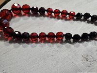 Close-up of faceted cherry amber and dark cherry amber beads of the necklace.