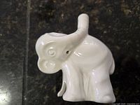 Front and side view of white ceramic elephant pie funnel with raised trunk that acts as the funnel spout