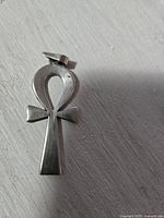 Front view of vintage silver Egyptian Ankh pendant on white surface