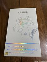 Box with Vraiko brand and Lily Collection printed, showing the product name as Neck & Face Beauty Massager with decorative floral artwork
