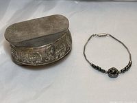 Silver elephant cuff bracelet and hematite beaded bracelet displayed together on white surface.