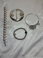 Full lot set showing all 4 items: three bracelets and one belt buckle on silver fabric