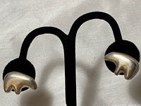 Pair of sterling silver bear claw stud earrings on a black earring display stand, front view showing left earring