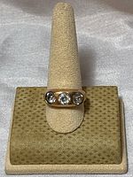 Front view of vintage gold filled ring with three clear crystals on display stand.