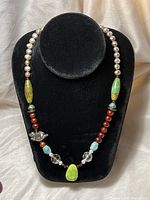 Full view of the necklace showing the bead arrangement with pearls, turquoise, garnet, and pig charm