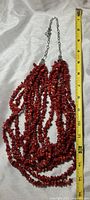Full view of the multi-strand red coral chip necklace alongside a tape measure showing approximate length at 26 inches.