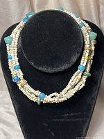 Close-up view of the multi-strand sea glass necklace showcasing white beads and various colored sea glass pieces.